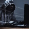 Faceless character with black gloves doing password hacking online within the mainframe